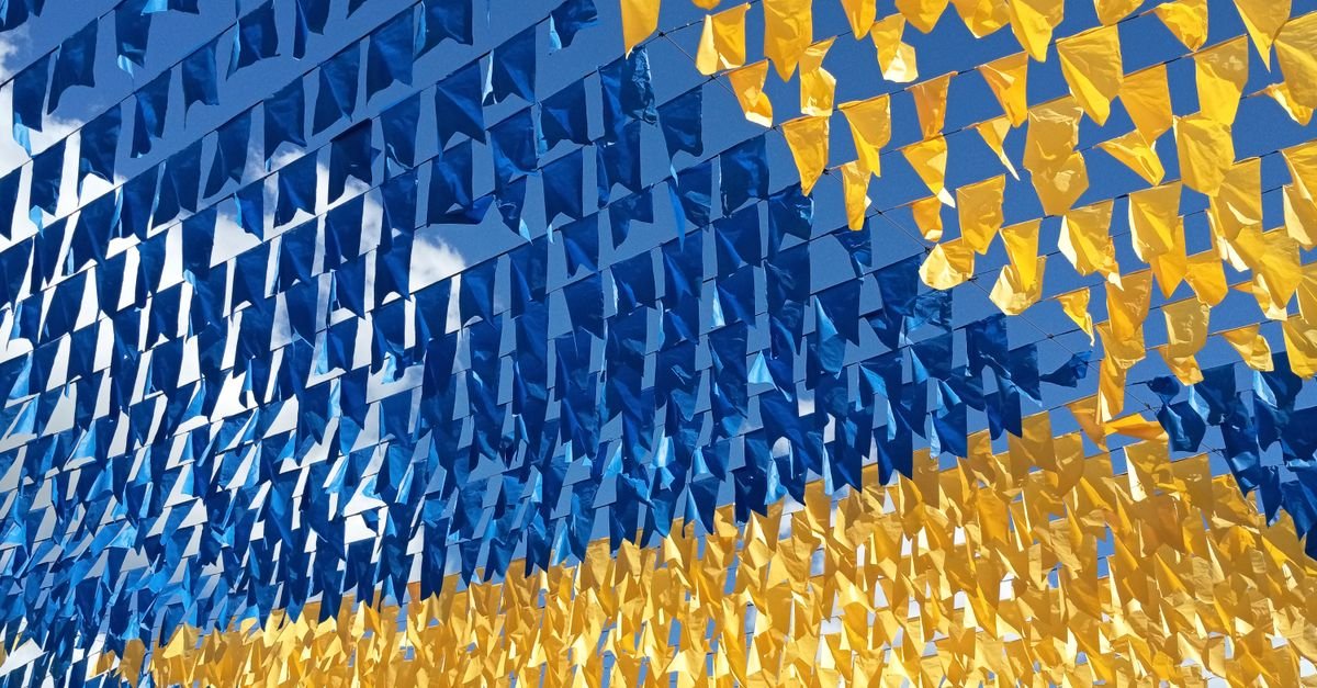 Colorful blue and yellow bunting flags flutter festively under a bright summer sky.