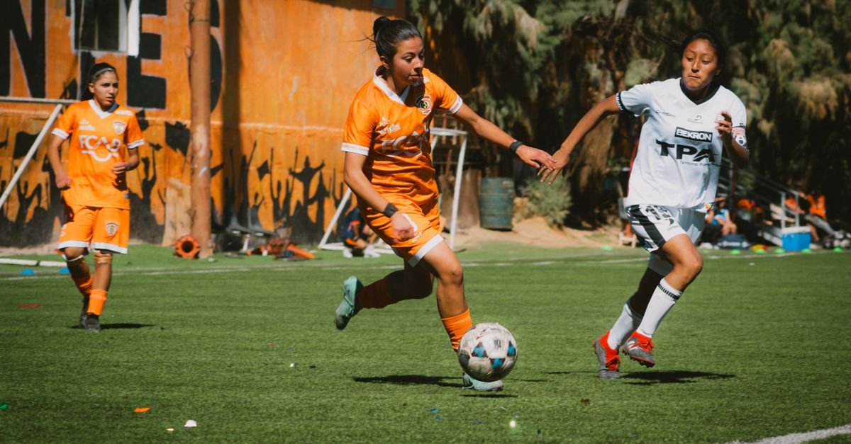 Exciting women's football match with players in action on a sunny day in Chile.