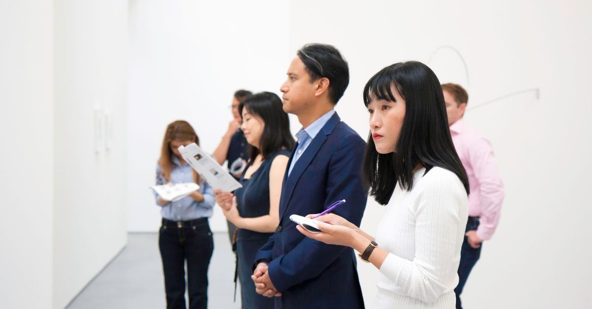 A group of people attentively viewing art installations in a modern gallery setting.