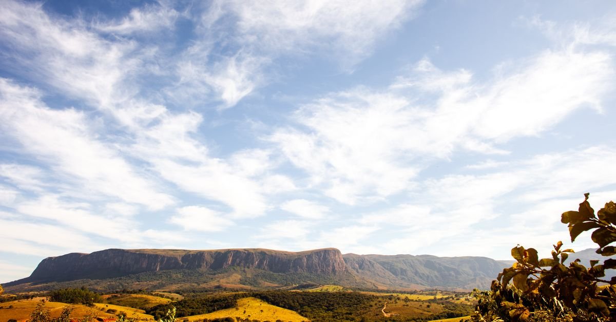 A breathtaking view of a mountain range with a clear blue sky and scattered clouds.