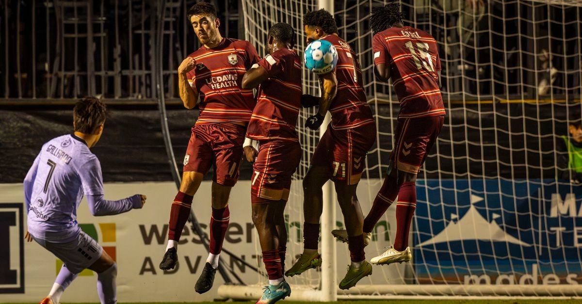 Intense soccer moment capturing a team's defensive wall blocking a free kick.