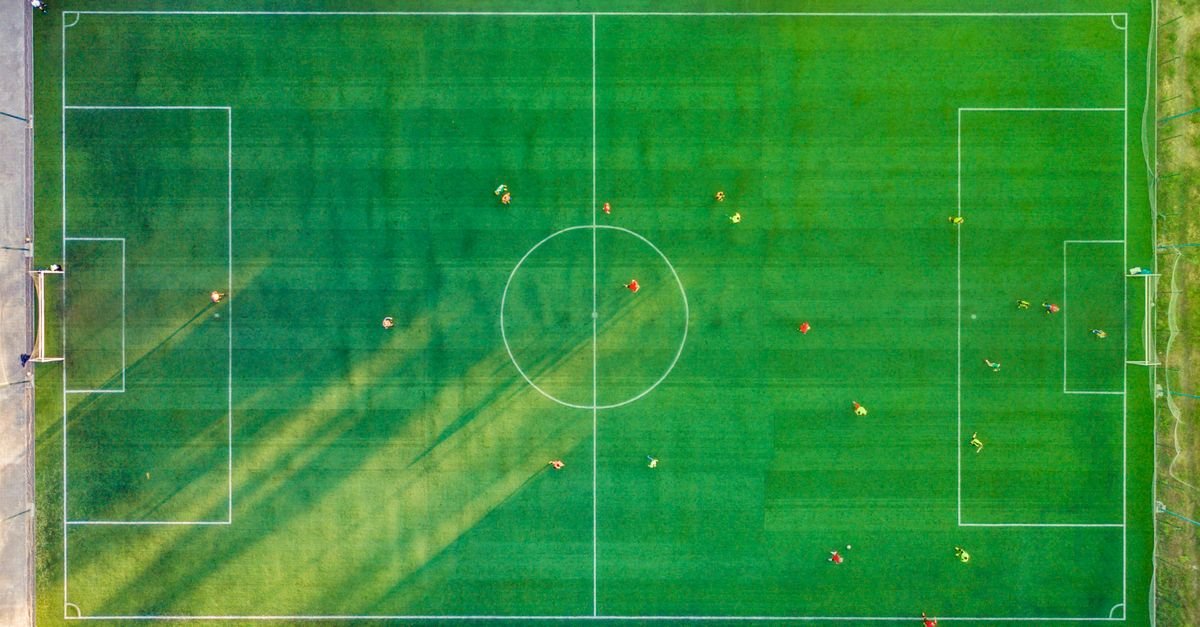 Aerial shot of a soccer game with players on a vibrant green field.