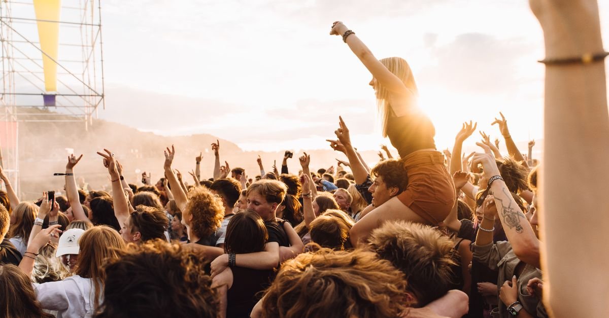 Energetic crowd enjoying live music at a festival during sunset.