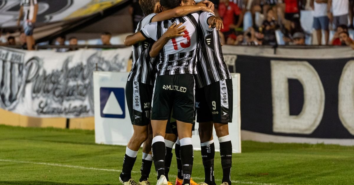Soccer players in a joyous group hug after scoring a goal, showcasing teamwork and celebration.