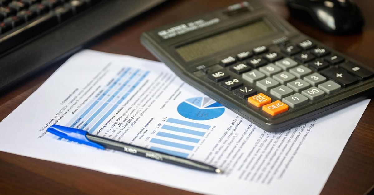 Desk with calculator, financial report, and pen, suggesting business analysis.