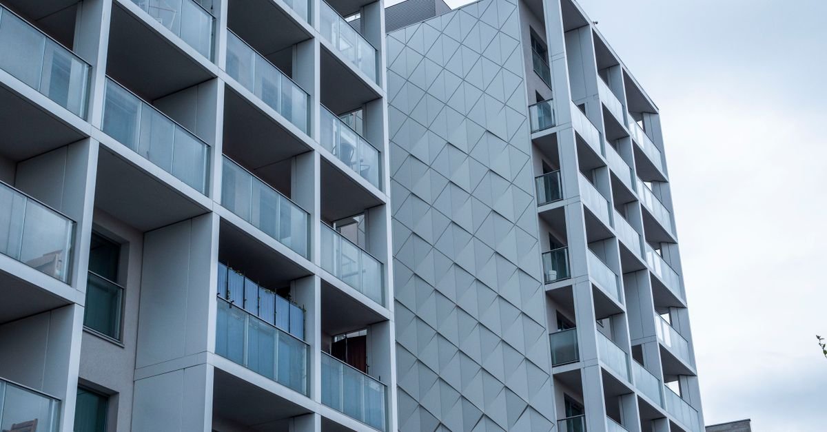 Contemporary glass facade of a city apartment building under a cloudy sky.