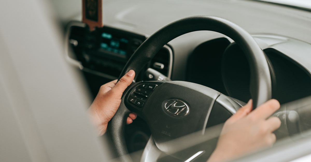 Close-up view of hands holding the steering wheel inside a car.