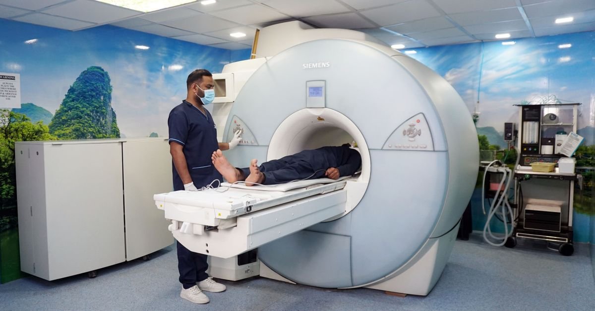 A medical technician assists a patient in an MRI machine in a healthcare facility, showcasing modern medical technology.