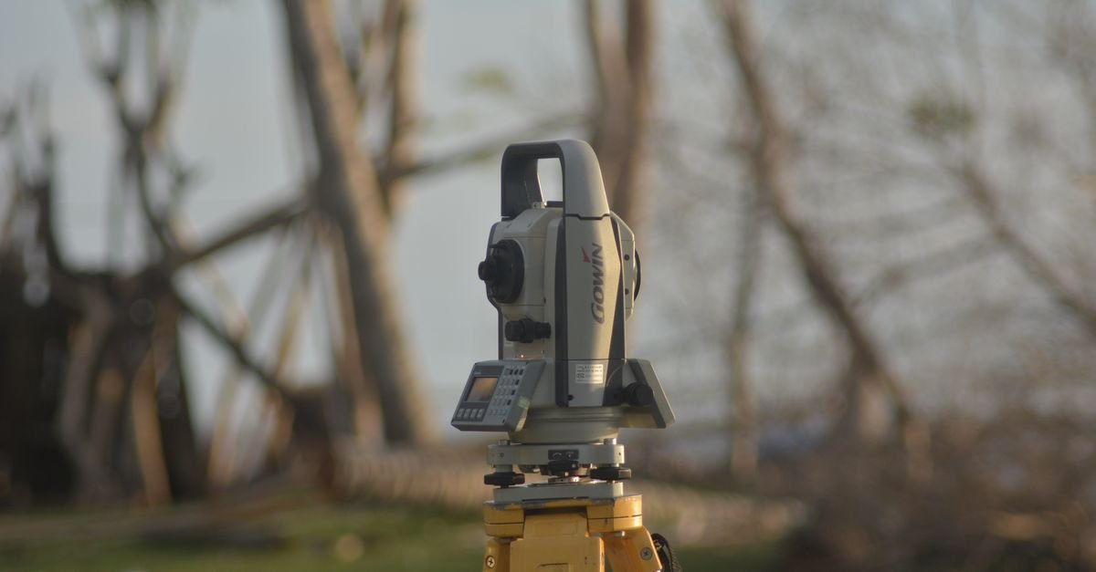 A precise total station used for geodetic surveying at a construction site with a natural background.