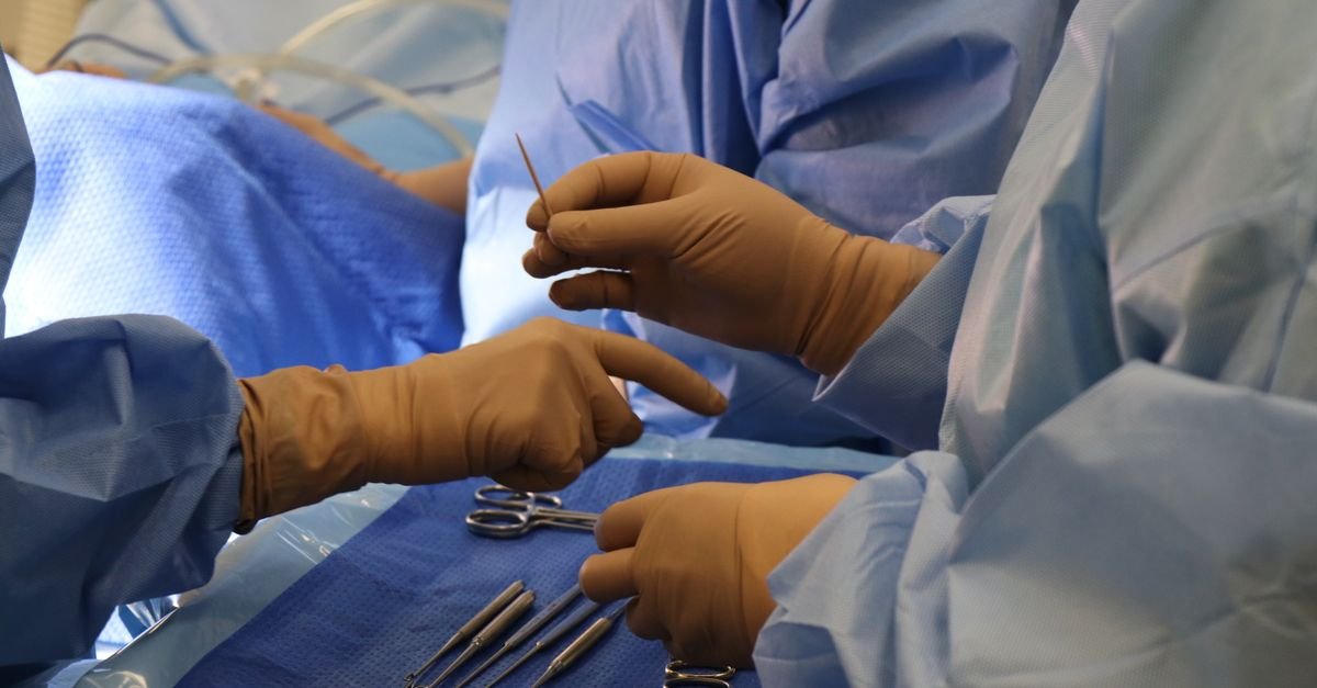 Surgeons in scrubs using medical tools during a surgical procedure