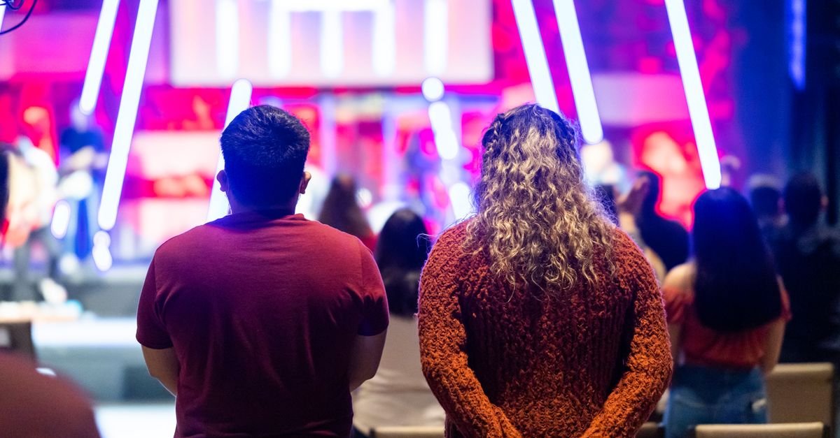 People attending a lively theater event with colorful neon lighting.
