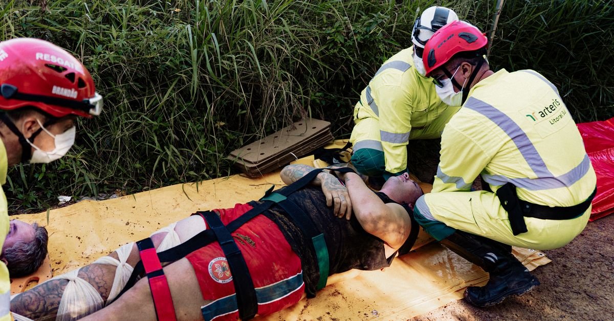 Rescue operation with paramedics attending to an injured person outdoors. Wearing protective helmets and face masks.