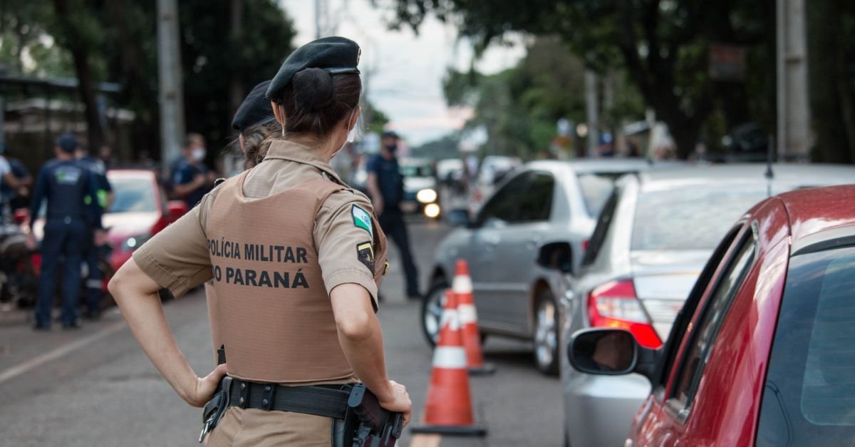Back view of a police officer in uniform controlling traffic on a busy road.