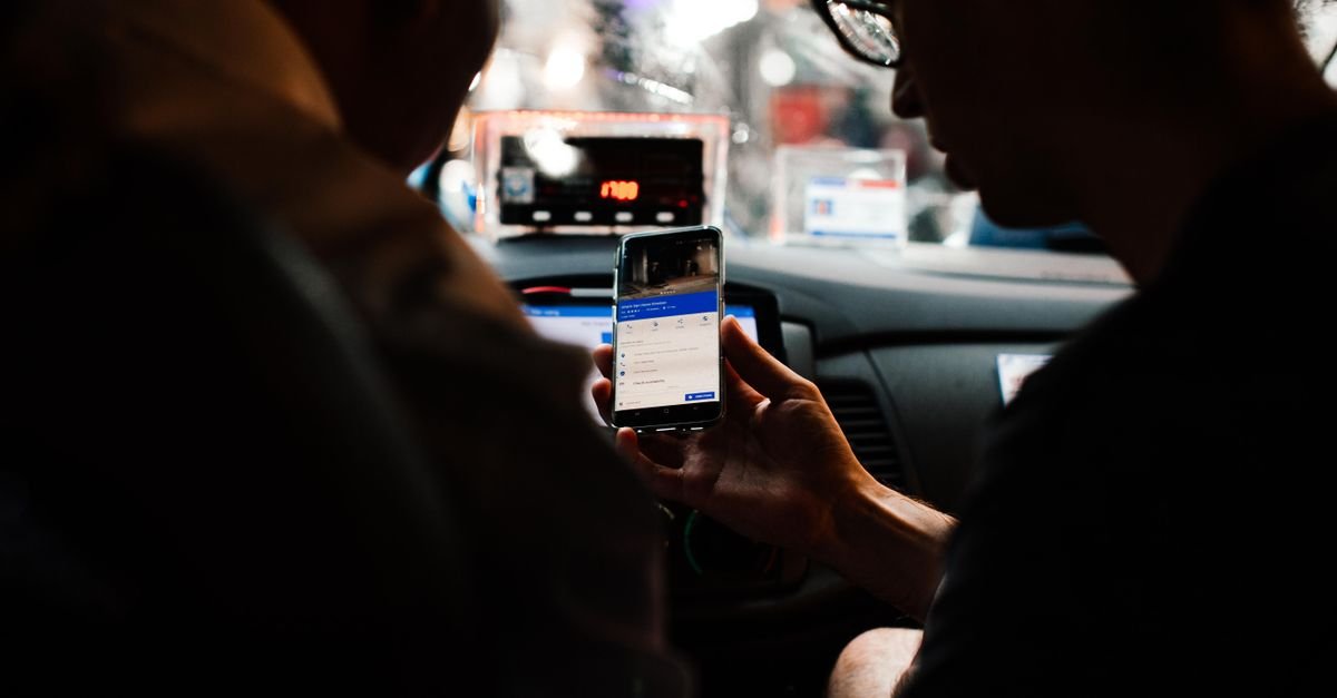 Two people using a smartphone for directions in a car at night.