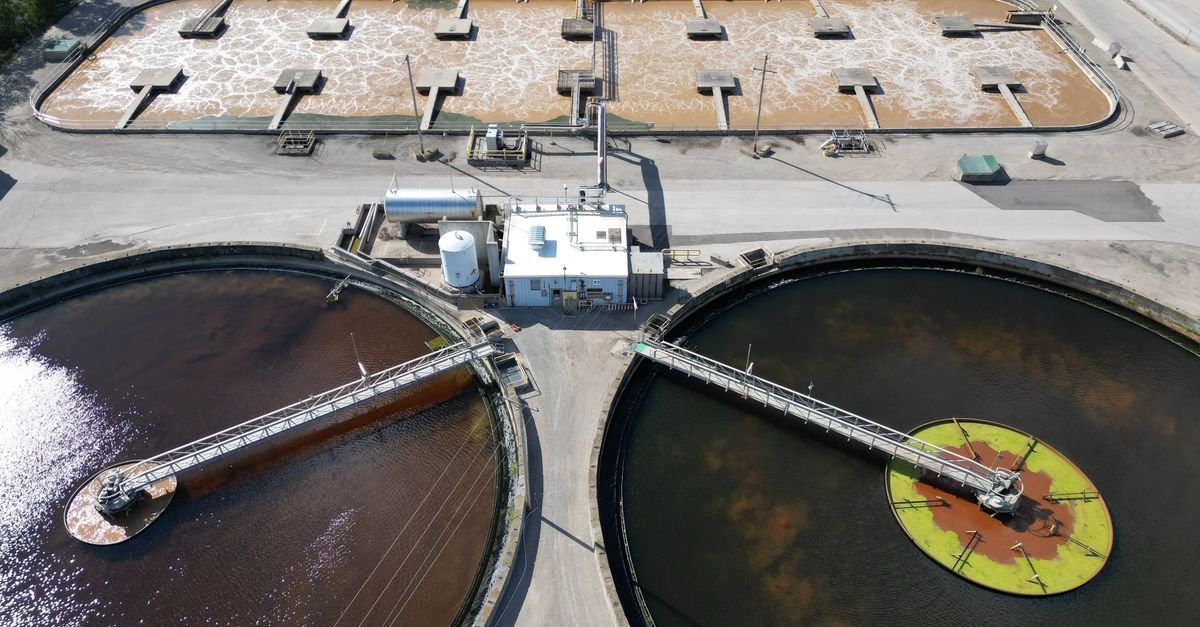 Aerial shot of an industrial water treatment plant with large circular tanks.
