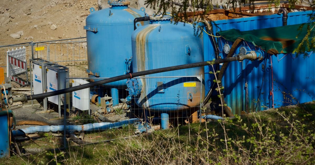 Outdoor industrial water filtration plant with large blue tanks under sunlight.