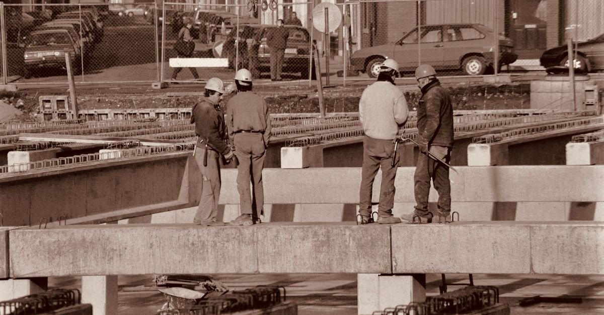 Group of construction workers discussing plans on an urban construction site.