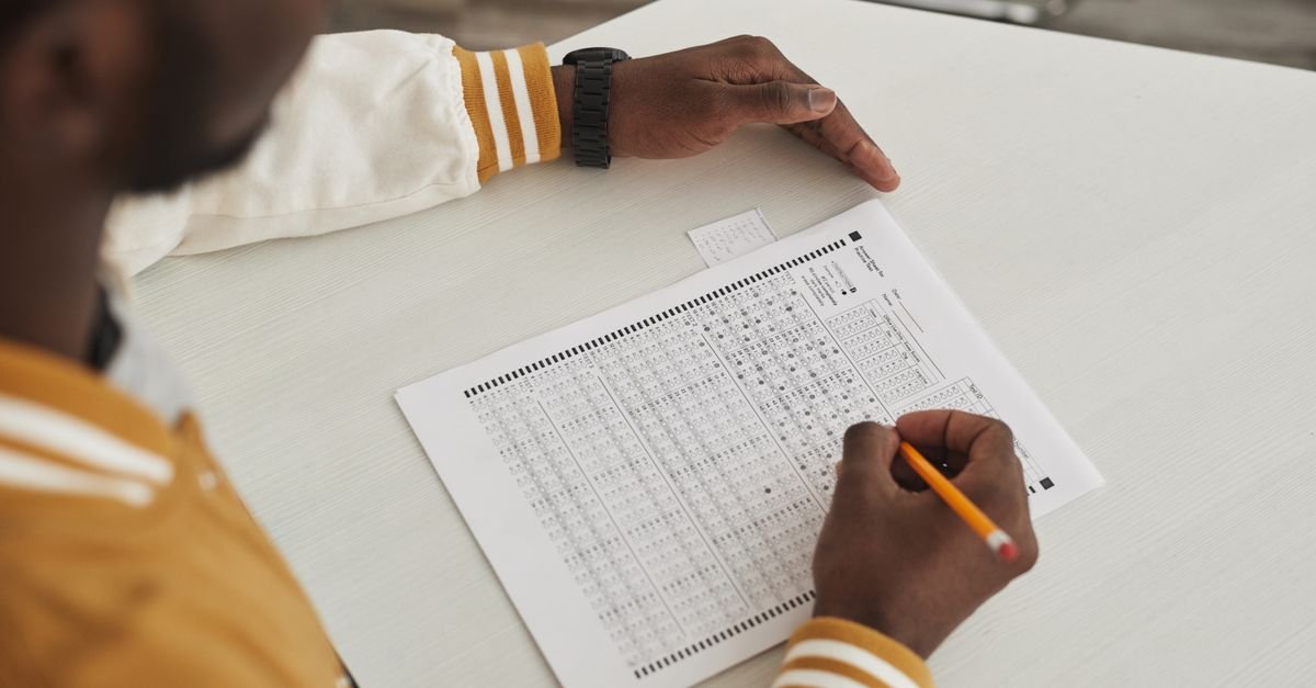 Focused student marking answers on a multiple choice exam sheet in a classroom setting.