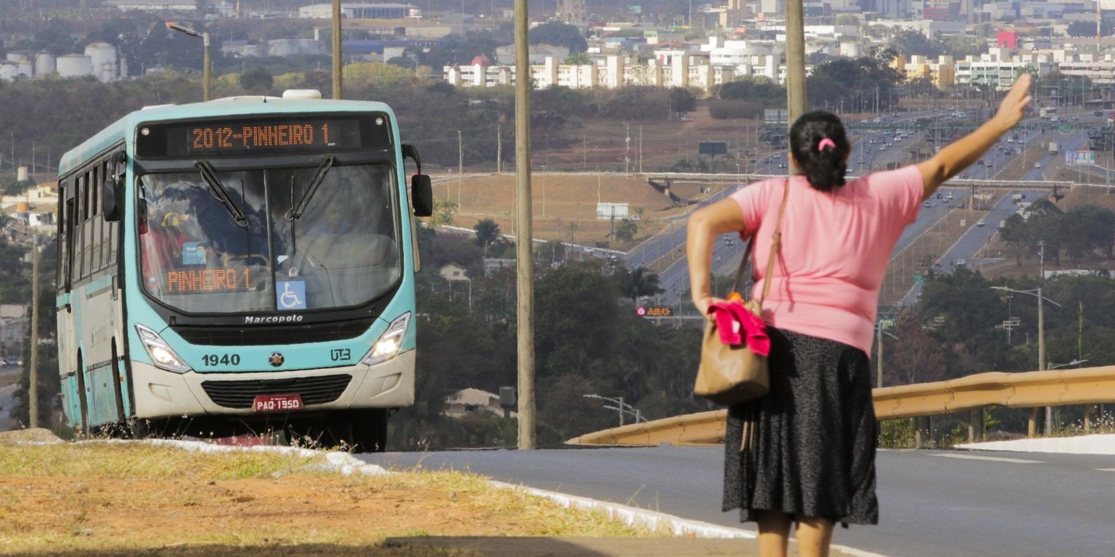 Mulher acena para ônibus da linha Pinheiro 1 em avenida do Distrito Federal