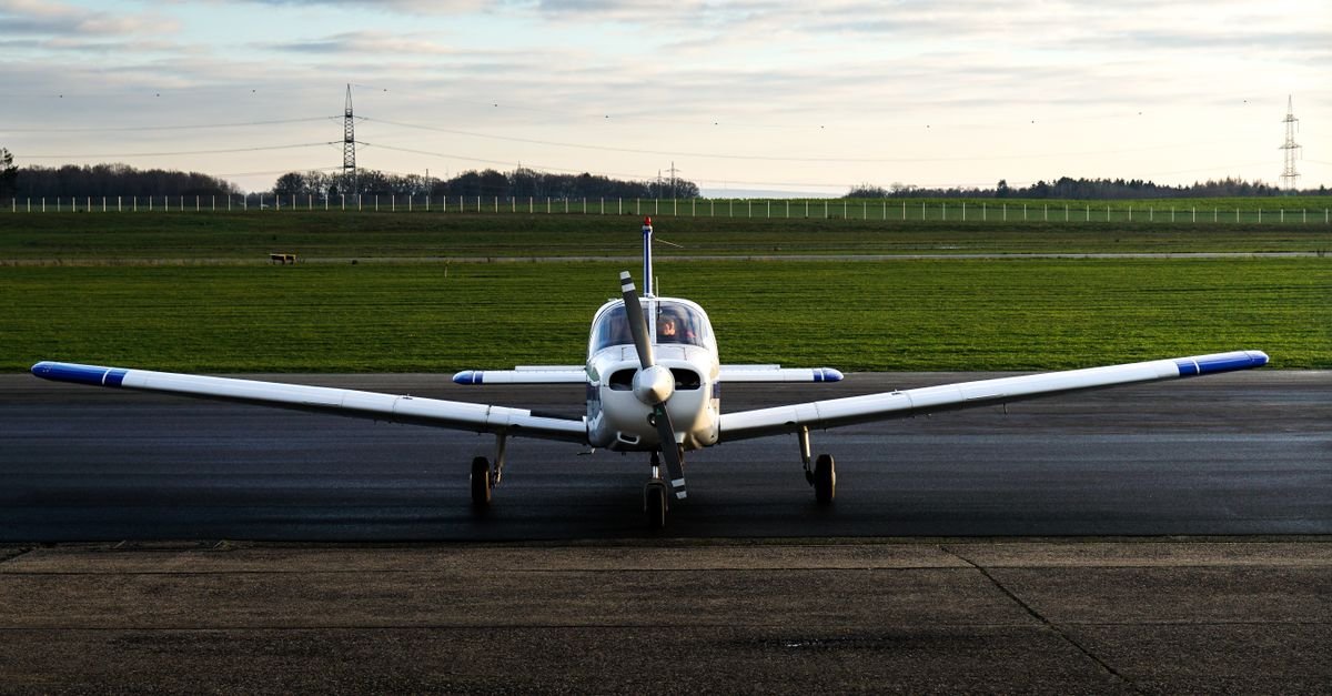 Avião monomotor de pequeno porte parado em pista ao entardecer