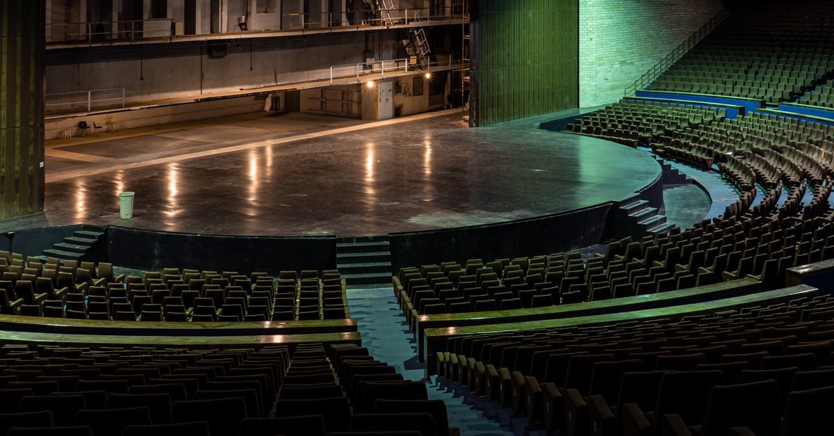 Palco de teatro vazio visto do alto, com fileiras de poltronas da plateia