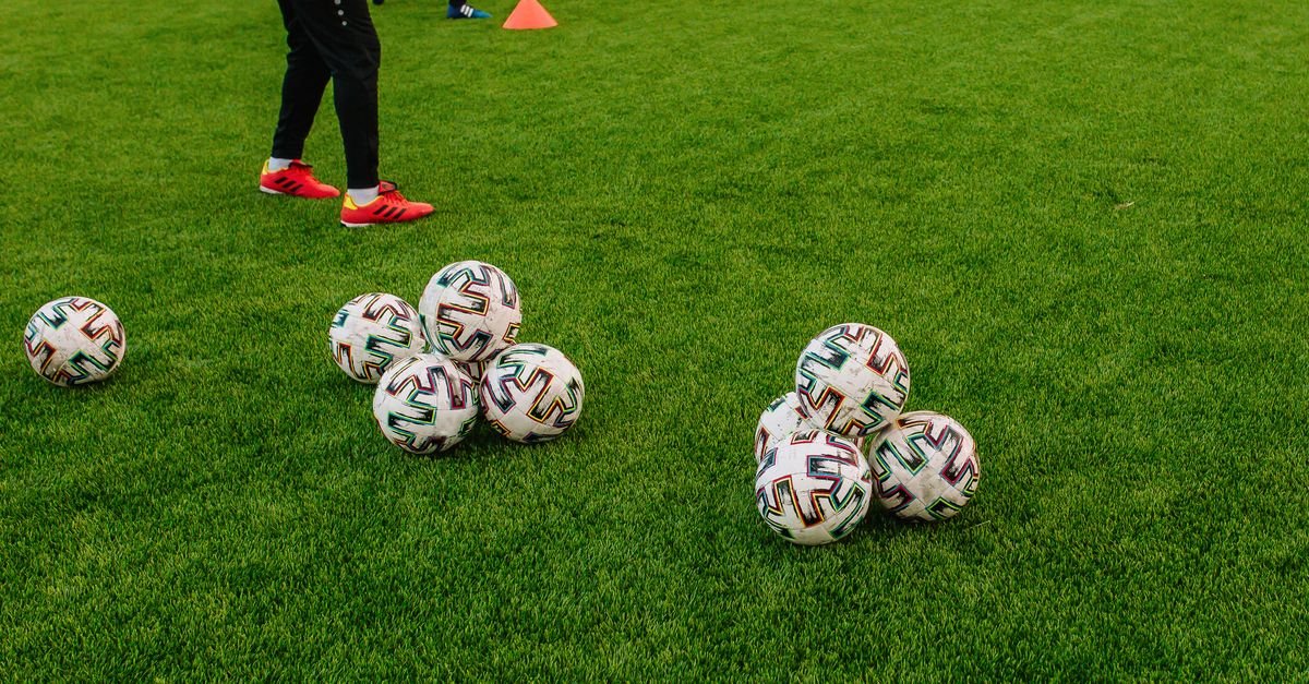 Bolas de futebol reunidas no gramado durante treino