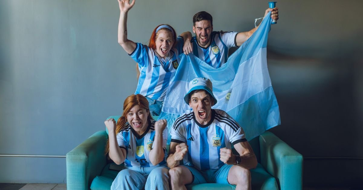 Torcedores da Argentina comemoram no sofá com bandeira e camisas da seleção