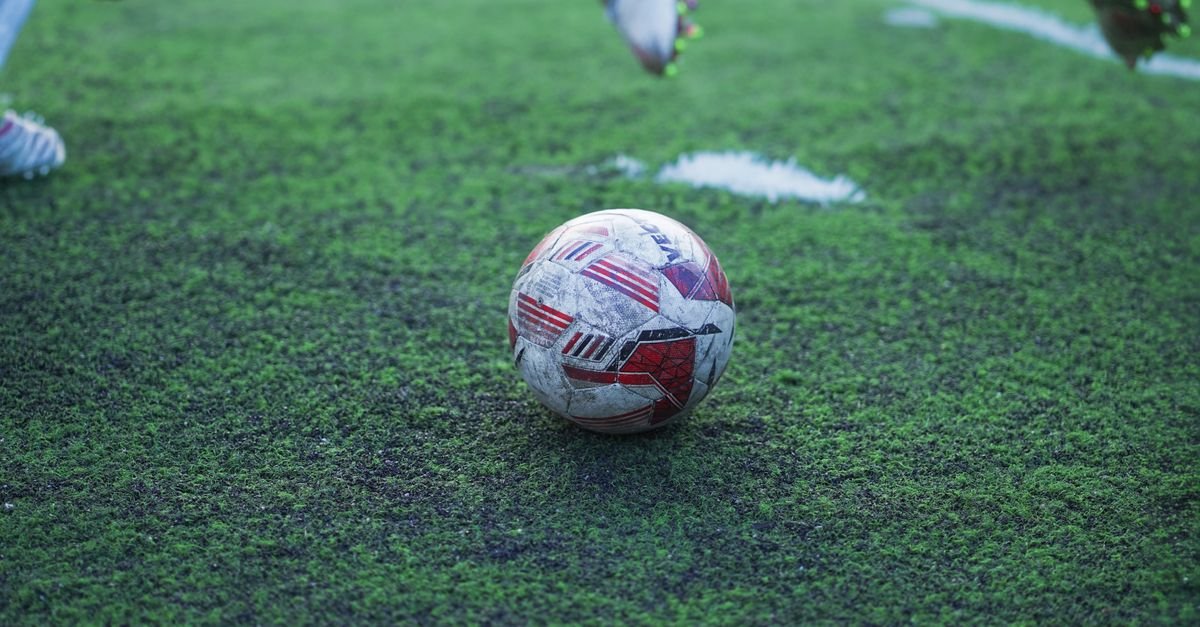 Bola de futebol sobre gramado sintético em campo de jogo