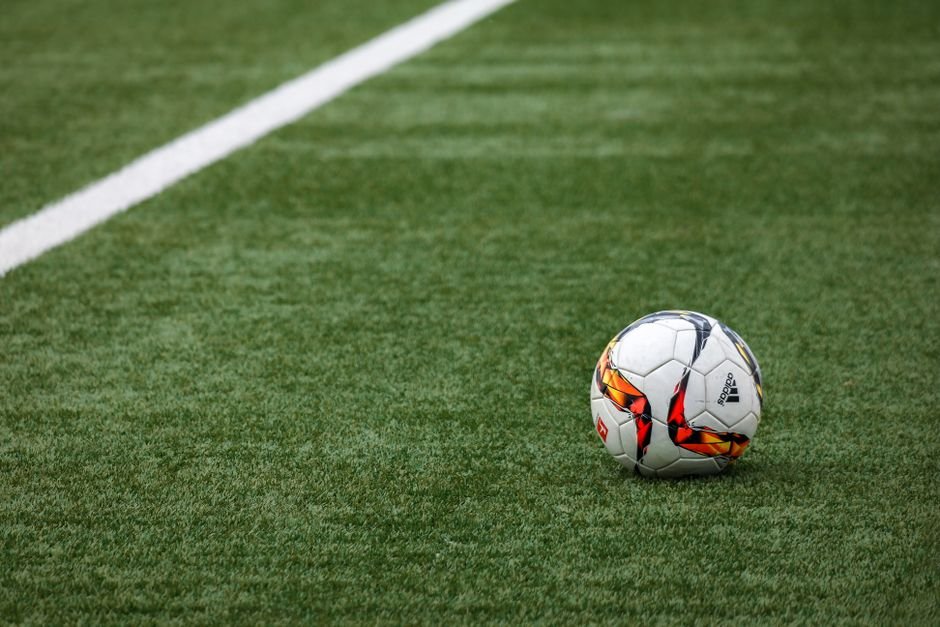 Bola de futebol sobre o gramado ao lado da linha do campo