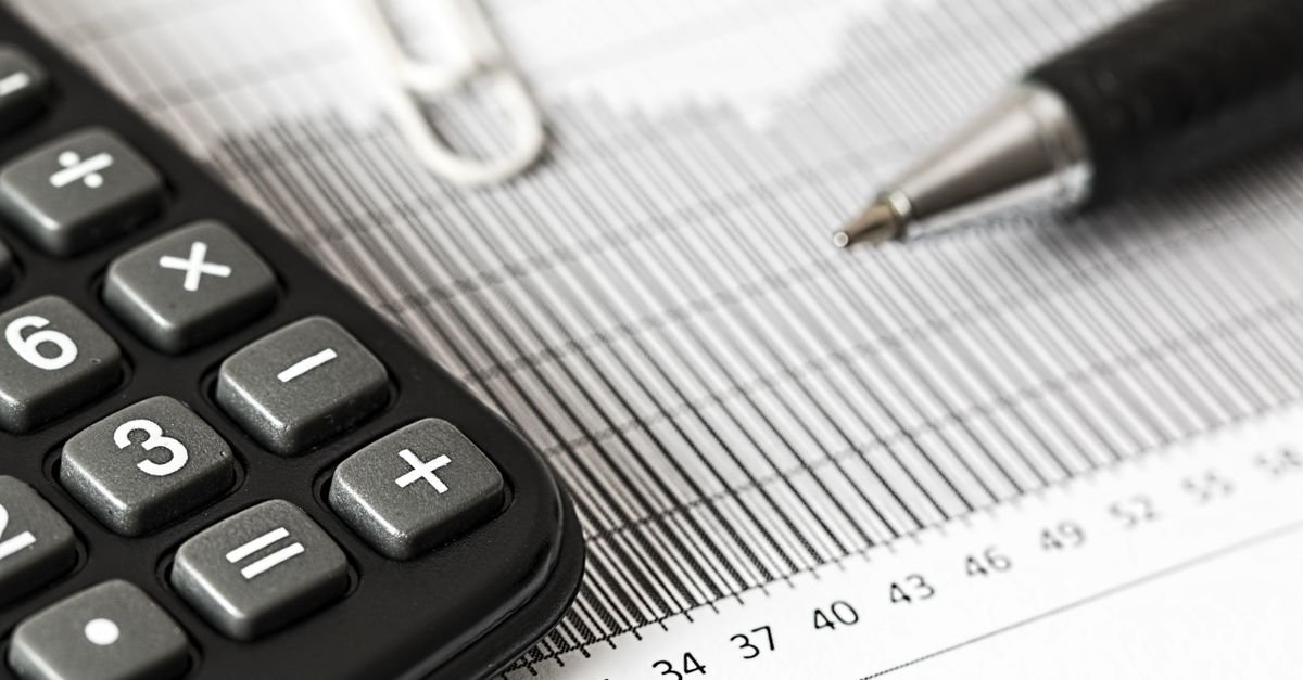 Calculadora e caneta sobre relatório impresso com gráfico de barras
