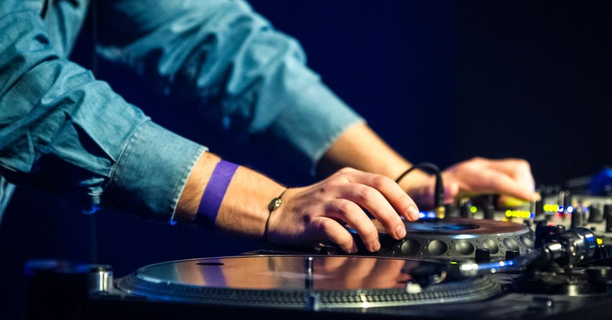 Mãos de DJ mixam discos de vinil em pick-ups durante apresentação