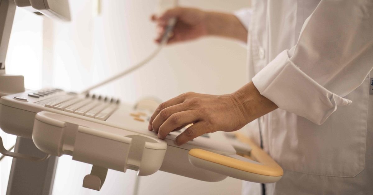 Mãos de profissional de saúde operando aparelho de ultrassom