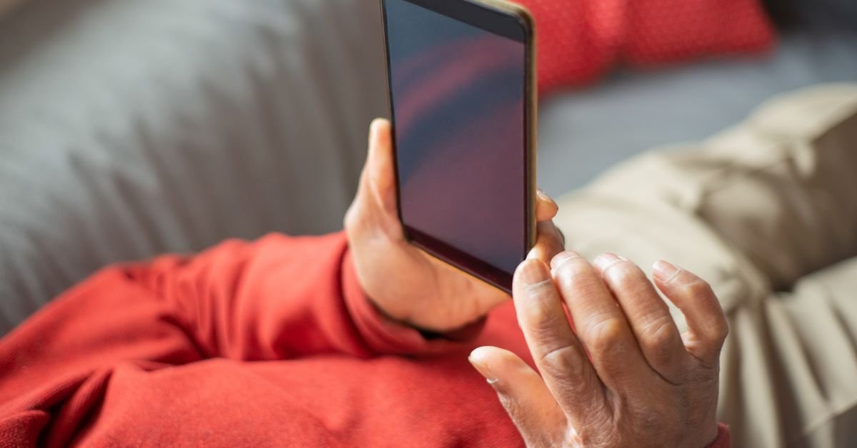 Idoso segura smartphone com as duas mãos
