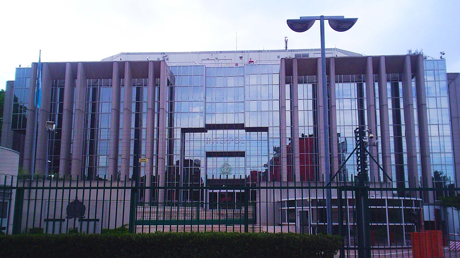 Fachada de vidro da sede da Interpol, em Lyon, na França, com o letreiro da organização