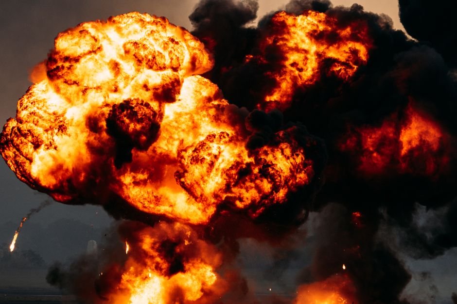 Explosão com bola de fogo e fumaça preta em área aberta