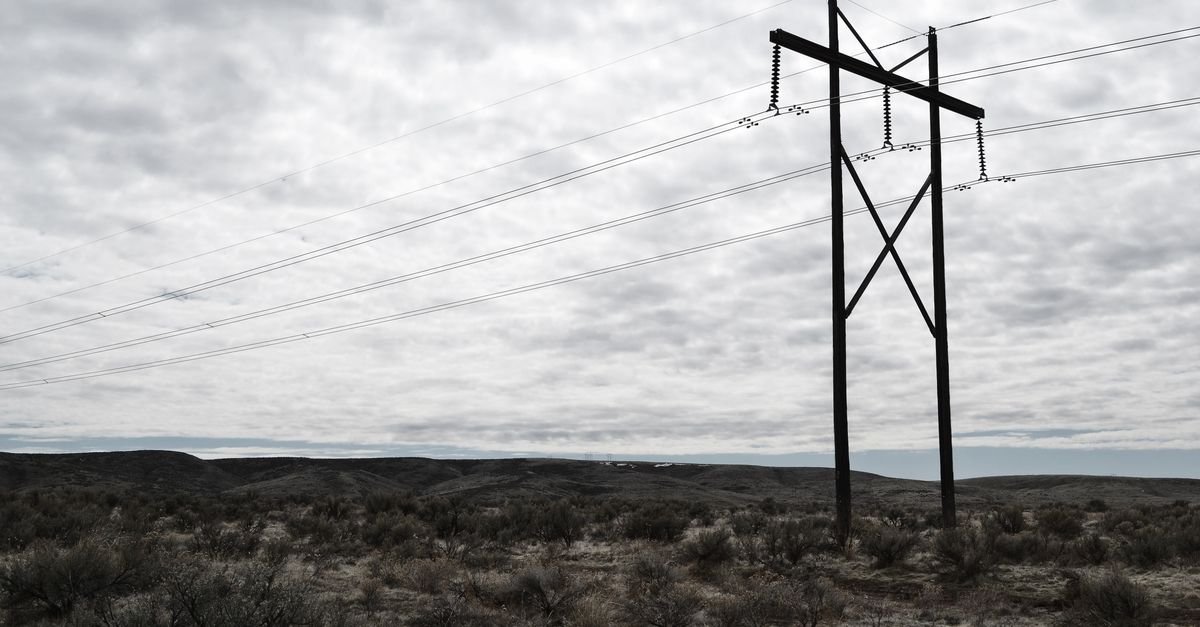 Torre de transmissão de energia elétrica com cabos contra céu nublado