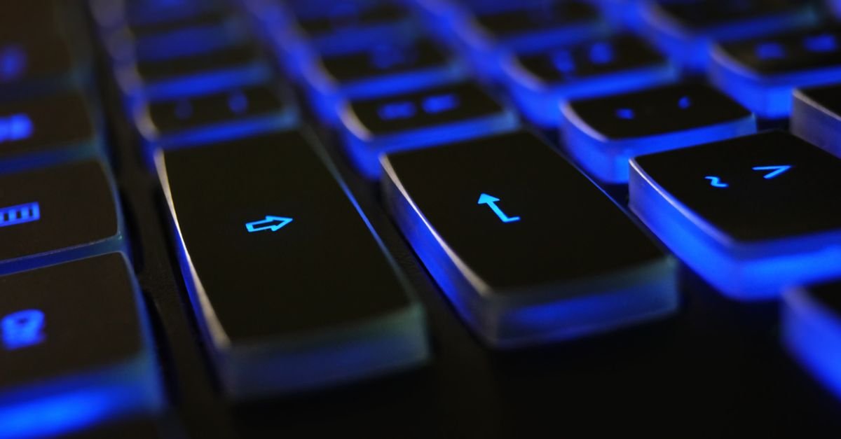 Teclado de computador com iluminação azul em ambiente escuro