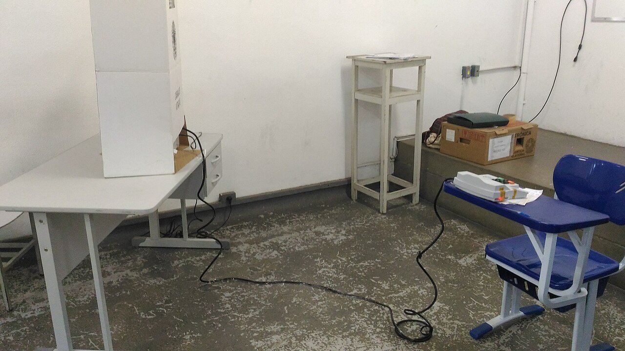Seção eleitoral montada em sala de escola, com cabine de votação e caixa de transporte de urna eletrônica