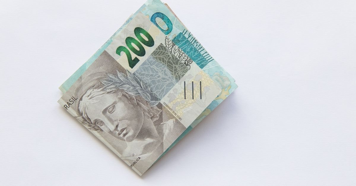 Maço de cédulas de duzentos reais dobradas sobre fundo branco, em referência ao lucro do FGTS