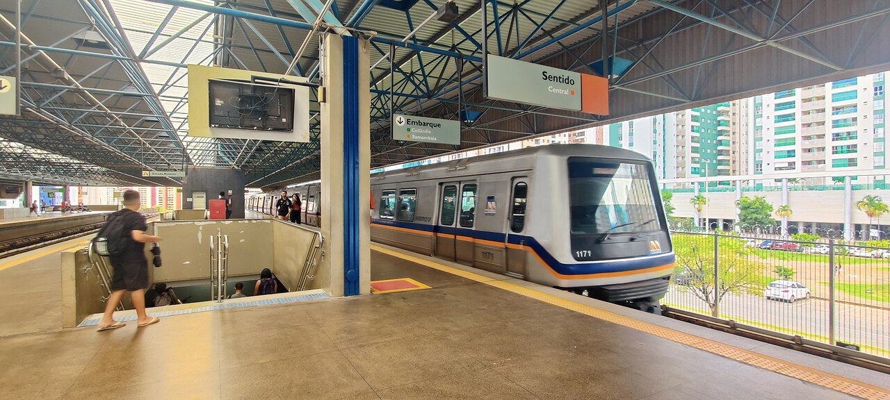 Trem do Metrô-DF parado na plataforma da estação Águas Claras, com placa indicando sentido Central