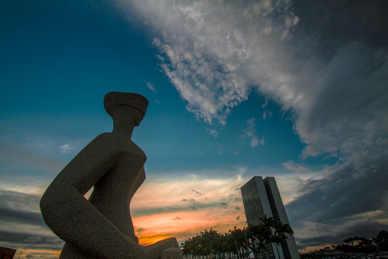 Escultura A Justiça, na Praça dos Três Poderes, com o Congresso Nacional ao fundo no fim da tarde