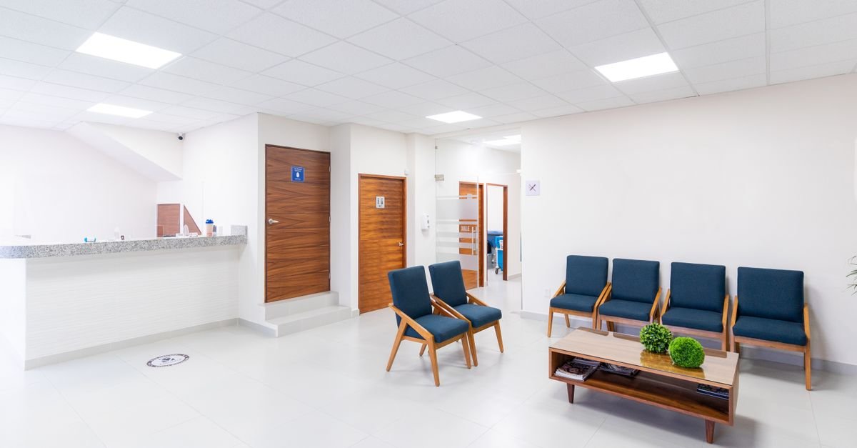 Recepção e sala de espera de unidade de saúde com cadeiras vazias