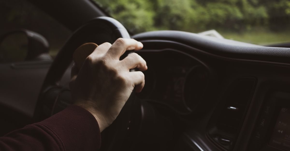 Mão de motorista sobre o volante de um carro em movimento