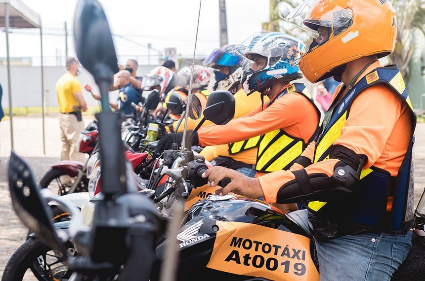 Fila de mototaxistas de colete laranja sobre motocicletas com a inscrição MOTOTÁXI