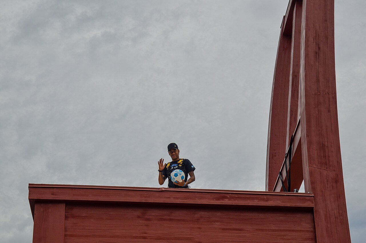 O atacante Neymar acena segurando uma bola de futebol durante evento público