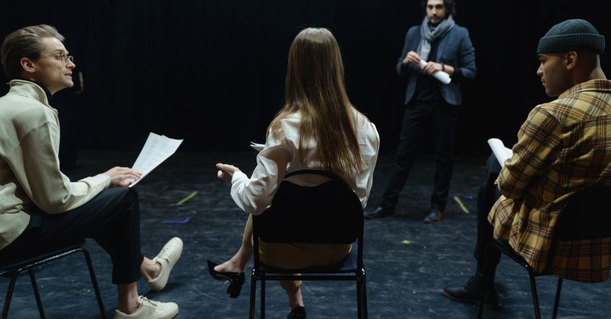 Jovens atores ensaiam com roteiros em palco de teatro