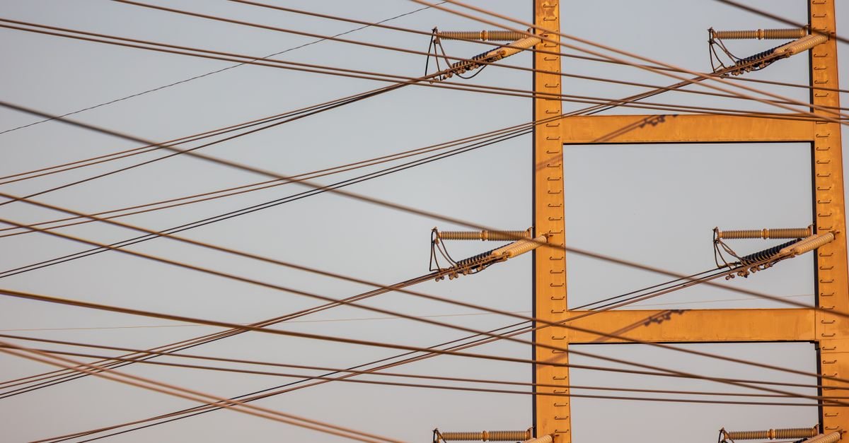Poste de energia elétrica com fiação e isoladores contra o céu azul