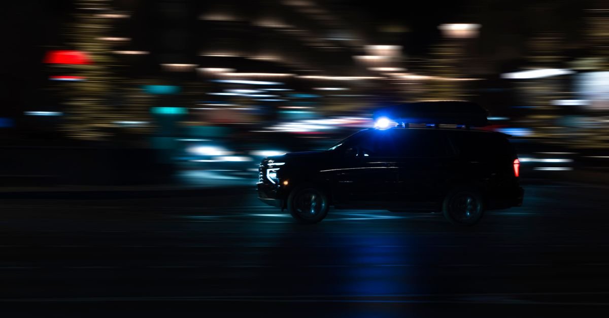 Viatura policial em deslocamento noturno com giroflex azul aceso