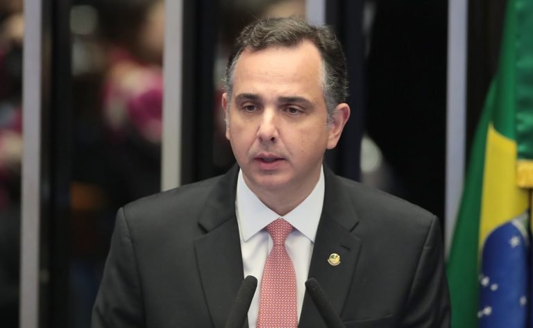 Senador Rodrigo Pacheco discursa em tribuna ao lado da bandeira do Brasil