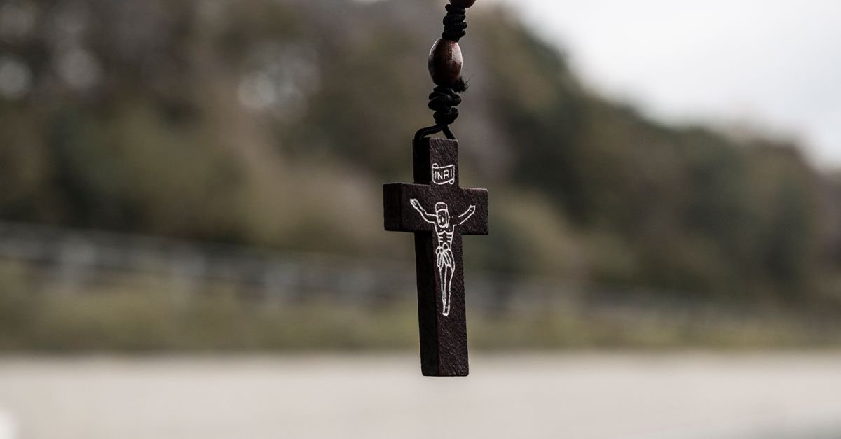 Crucifixo de madeira pendurado em close, com fundo desfocado